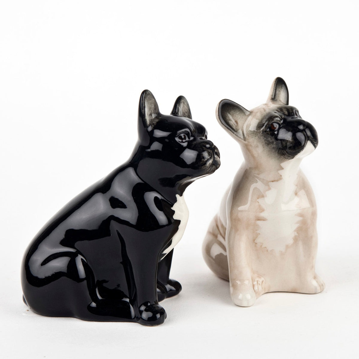 The QUAIL DESIGNS QUAIL CERAMICS - FRENCH BULLDOG SALT AND PEPPER SET features two handpainted stoneware French bulldogs, one glossy black and one matte beige with a darker face and ears, displayed side by side on a white background.