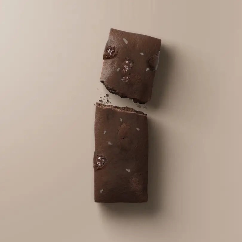 A STARS+HONEY - DARK CHOCOLATE COCONUT collagen protein bar is displayed on a coordinating beige background. The packaging emphasizes this low sugar protein bar from STARS+HONEY, highlighting that each bar contains 10g collagen, 13g protein, and only 2g sugar.