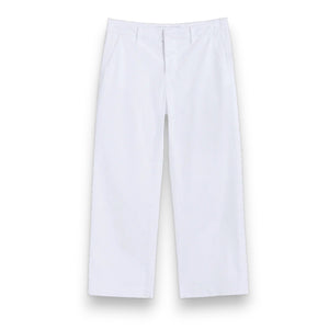 Outdoors on a pathway, a person wears FRANK & EILEEN's WESTPORT Italian Wide Leg Chino in Performance Twill White, paired with a light pink long-sleeve top and beige slide sandals. Green grass and blurred shrubbery appear in the background.