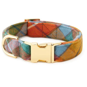 Two BUCHANAN PLAID DOG COLLARS from THE FOGGY DOG, each featuring gold metal buckles and D-rings, showcase a vibrant plaid pattern in blue, orange, yellow, and pink tones on a white surface.