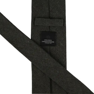 A close-up of the AMANDA CHRISTENSEN Jacquard Linen Tie in dark olive highlights the refined elegance of men’s accessories, featuring a rich textured design and a signature black label reading “Amanda Christensen, Sweden 1885” stitched on the back.