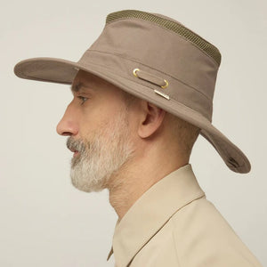 A man with a gray beard and mustache wears the TILLEY Airflo Hikers Hat T4MO-1 in olive, featuring UPF 50+ sun protection, and a beige button-up shirt, looking directly at the camera against a plain light background.
