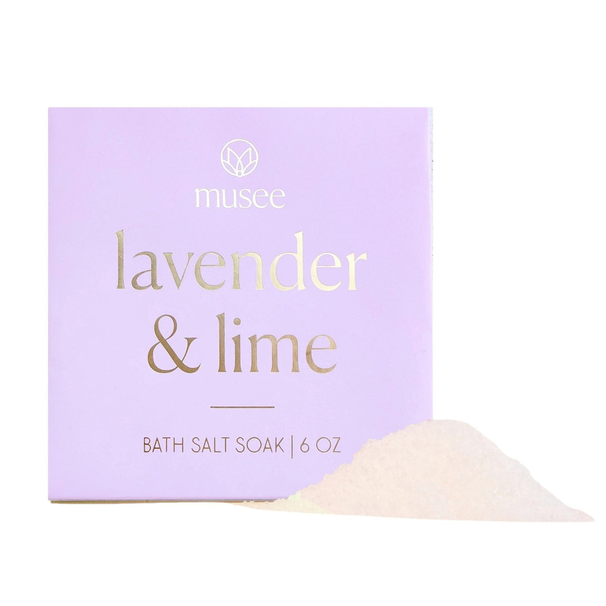 A lavender-colored box labeled “MUSEE - LAVENDER & LIME MINI BATH SALT SOAK” sits beside a small mound of white bath salts, infused with calming lavender essential oil for a soothing soak.