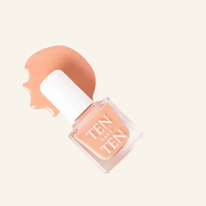 A glass bottle of TENOVERTEN - NAIL POLISH from the brand TEN OVER TEN, featuring a white cap and a dusty pink nail color. The front label displays "TEN OVER TEN" in white uppercase letters. This vegan, eight-free formula ensures both beauty and peace of mind. The background is plain and light-colored.