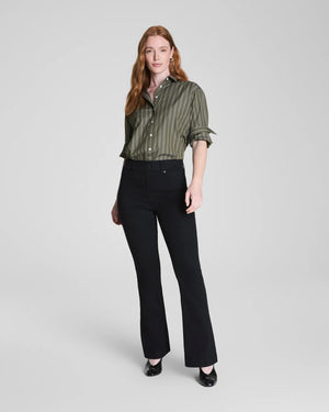 A person is shown from the back, wearing the SPANX - SPANXSHAPE EVERYWHERE PULL ON FLARE JEAN IN OBSIDIAN RINSE by SPANX with a green striped shirt, standing against a plain background to highlight the fit and style of the jeans.