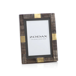 The ZODAX LAGOS HARN AND BRASS PHOTO FRAME 5x7 features textured dark brown and gold accents with a "ZODAX, Five Inches x Seven Inches" insert, adding elegance to your decor.