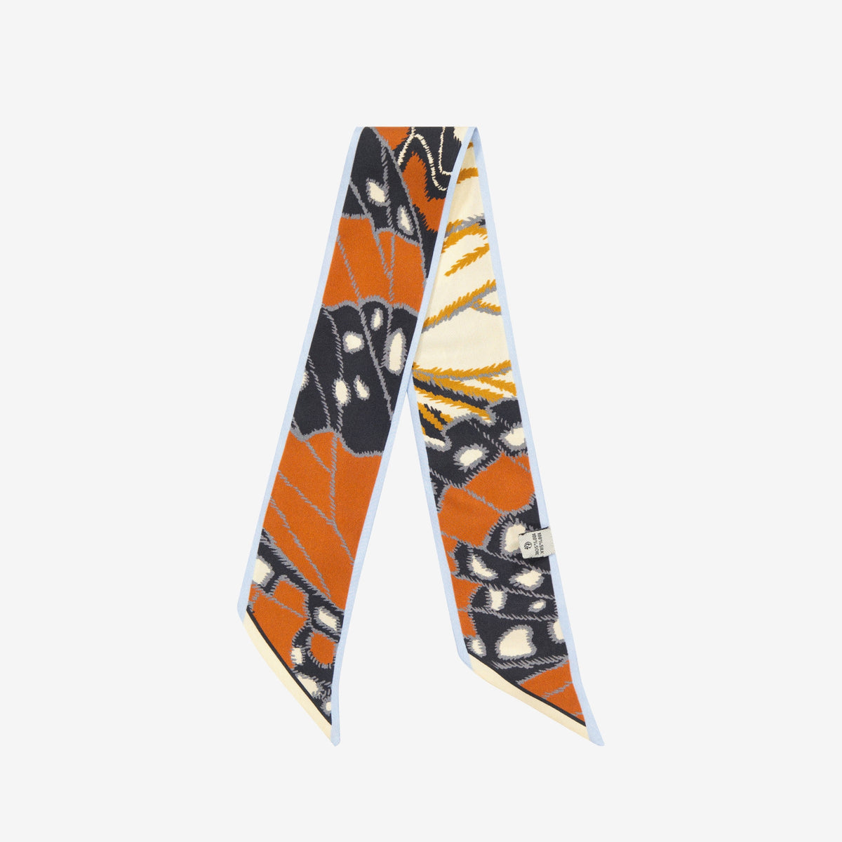 The INOUI EDITIONS - PAPILLON (BUTTERFLIES) SILK RIBBON by INOUI features a butterfly wing print in orange, black, white, and yellow—an elegant silk scarf to elevate any outfit. Displayed on a white background.