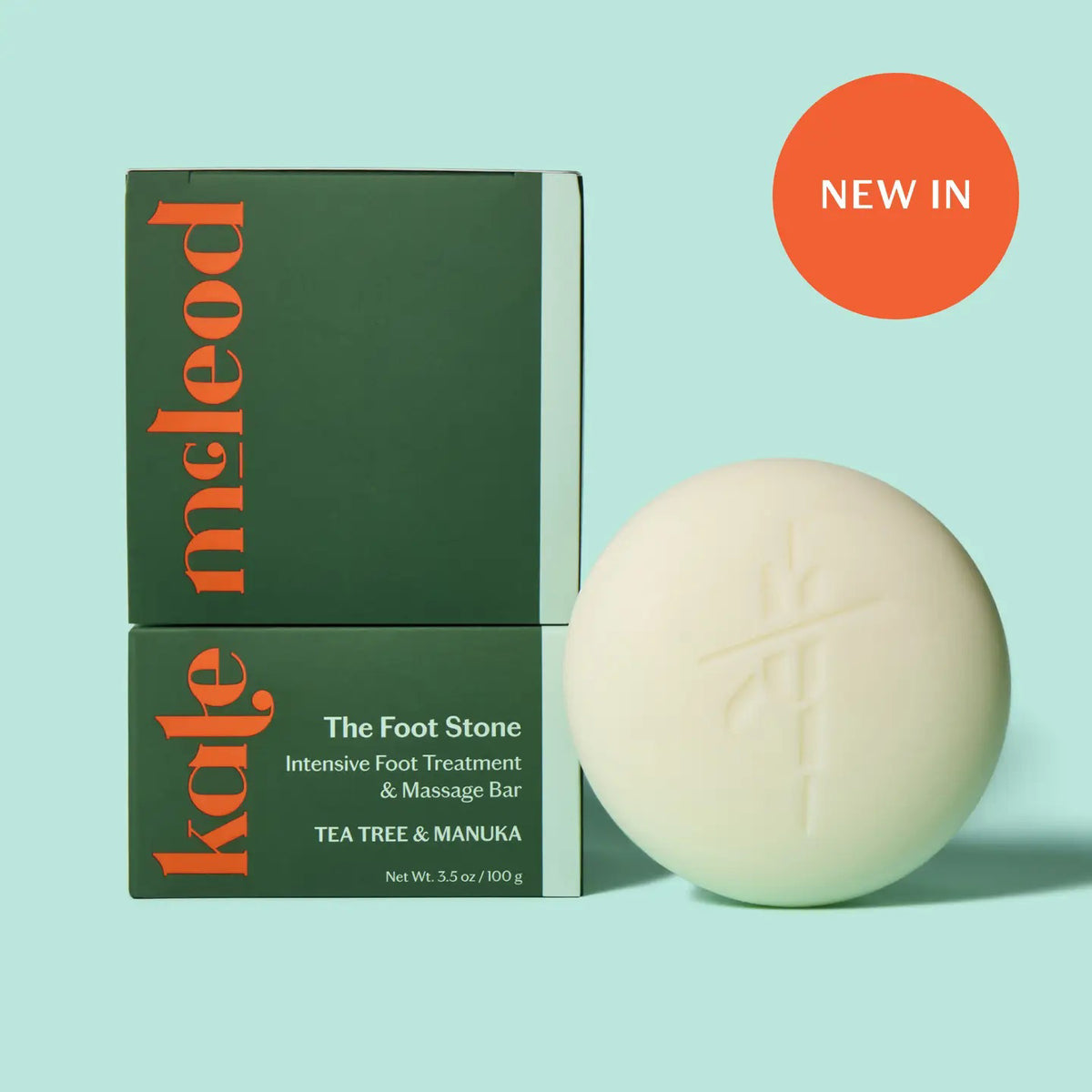 A person uses KATE MCLEOD’s THE FOOT STONE SOLID FOOT MOISTURIZER on their foot, holding the off-white round bar with one hand while the other rests on their ankle. The solid beige background emphasizes care for dry, cracked heels.