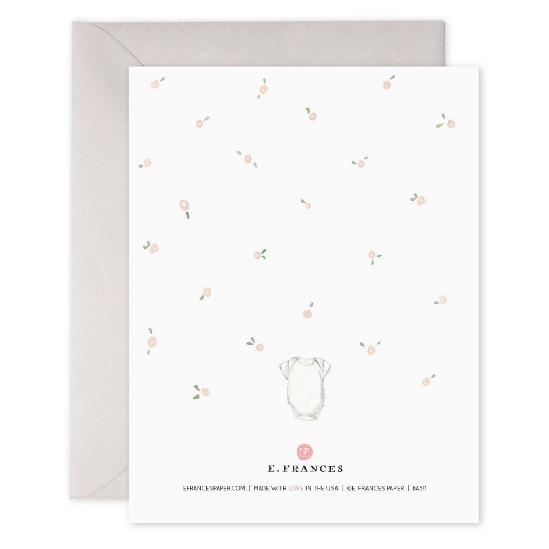 E. FRANCES PAPER - HELLO SWEET BUNDLE greeting card features a baby in a cradle with scattered pink flowers on a white background. The text "hello sweet bundle" is printed on heavyweight paper with gold foil accents, and the edge of the card is visible.