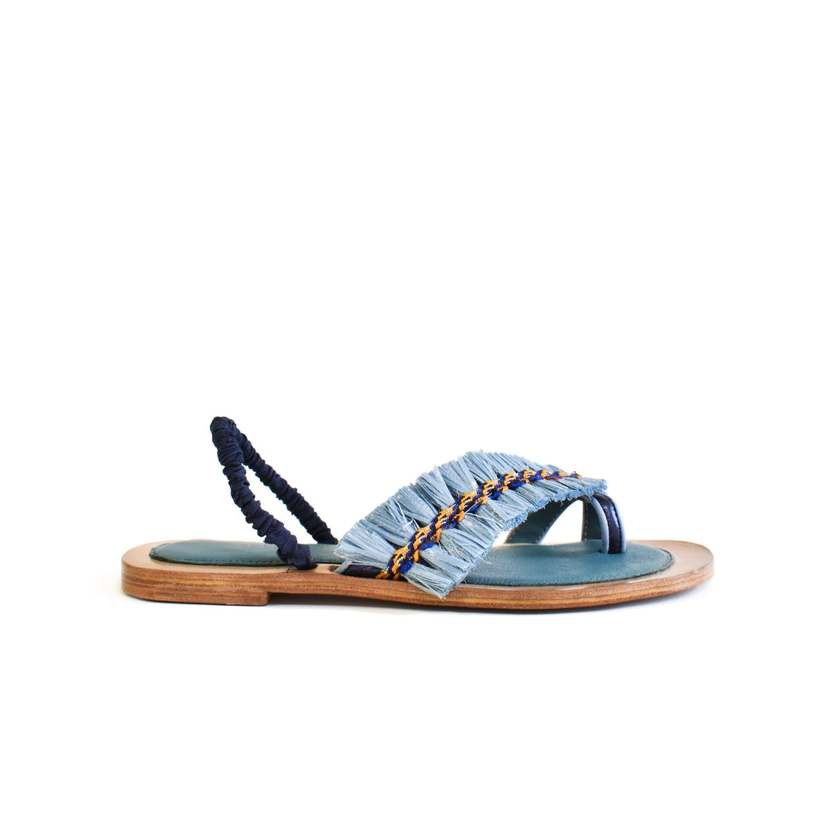 The MEHER KAKALIA - HAMAM SLIDE IN SONIC SAPHIRE is a single toe-ring sandal with a teal footbed, tan sole, and blue, yellow, and white raffia upper with fringe. "Meher Kakalia" is inscribed in gold script on the insole.