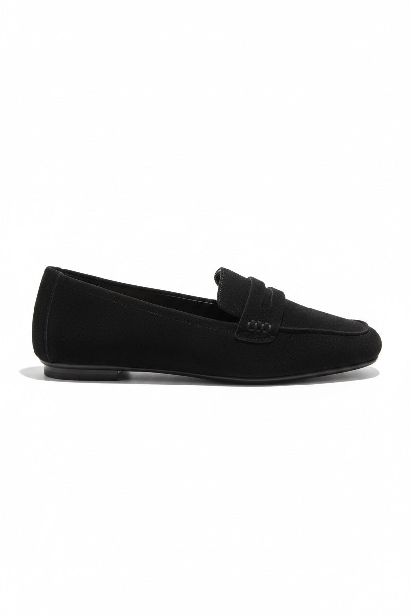 The REQINS HEMA Suede Loafer in Noir features a classic black silhouette, low heel, leather insole, and decorative front strap, shown against a plain light background.