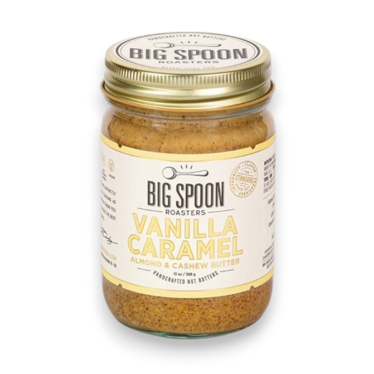 A 13 oz (368g) glass jar of BIG SPOON ROASTERS Vanilla Caramel Almond &amp; Cashew Butter features a gold lid and cream label, and contains handcrafted, refined sugar free, vegan nut butter from BIG SPOON ROASTERS.