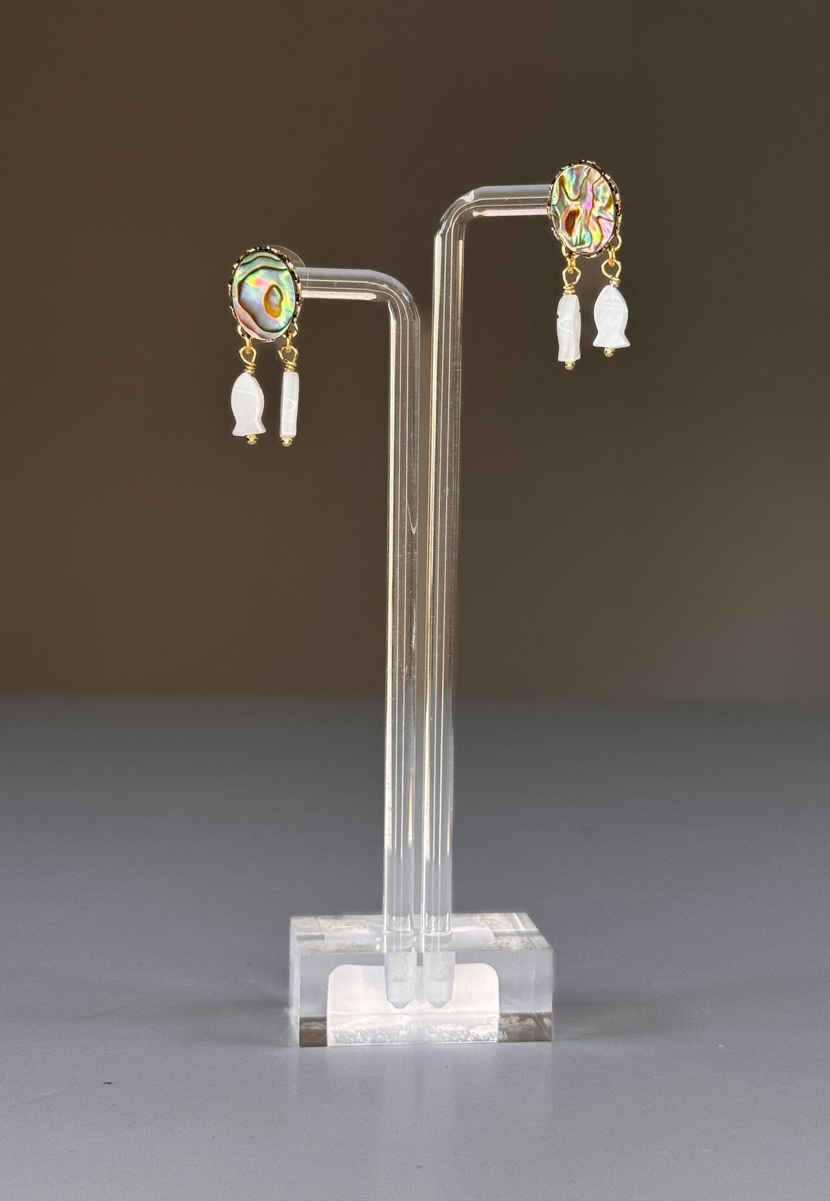 SANDRINE FRANCE STUDIO MINI Earrings: Handmade gold earrings with oval abalone cabochons featuring blue-green iridescence, each accented by two small Mother of Pearl fish charms. Crafted in NYC by SANDRINE FRANCE STUDIO.