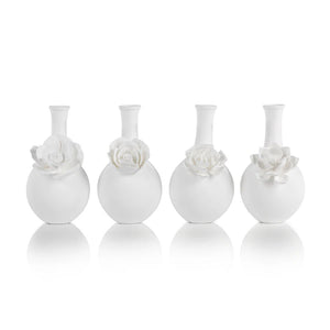 The CAMEO LONG NECK PORCELAIN BUD VASE by ZODAX is a round, white vase with a matte finish, featuring a narrow neck and a detailed floral embellishment on the front.