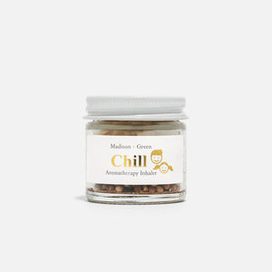 A small glass jar with a layered dessert and woven pastry crust sits on a white surface in sunlight. Nearby rests the MADISON AND GREEN - CHILL AROMATHERAPY INHALER by MADISON GREEN, as shadows and light patterns play across the scene.