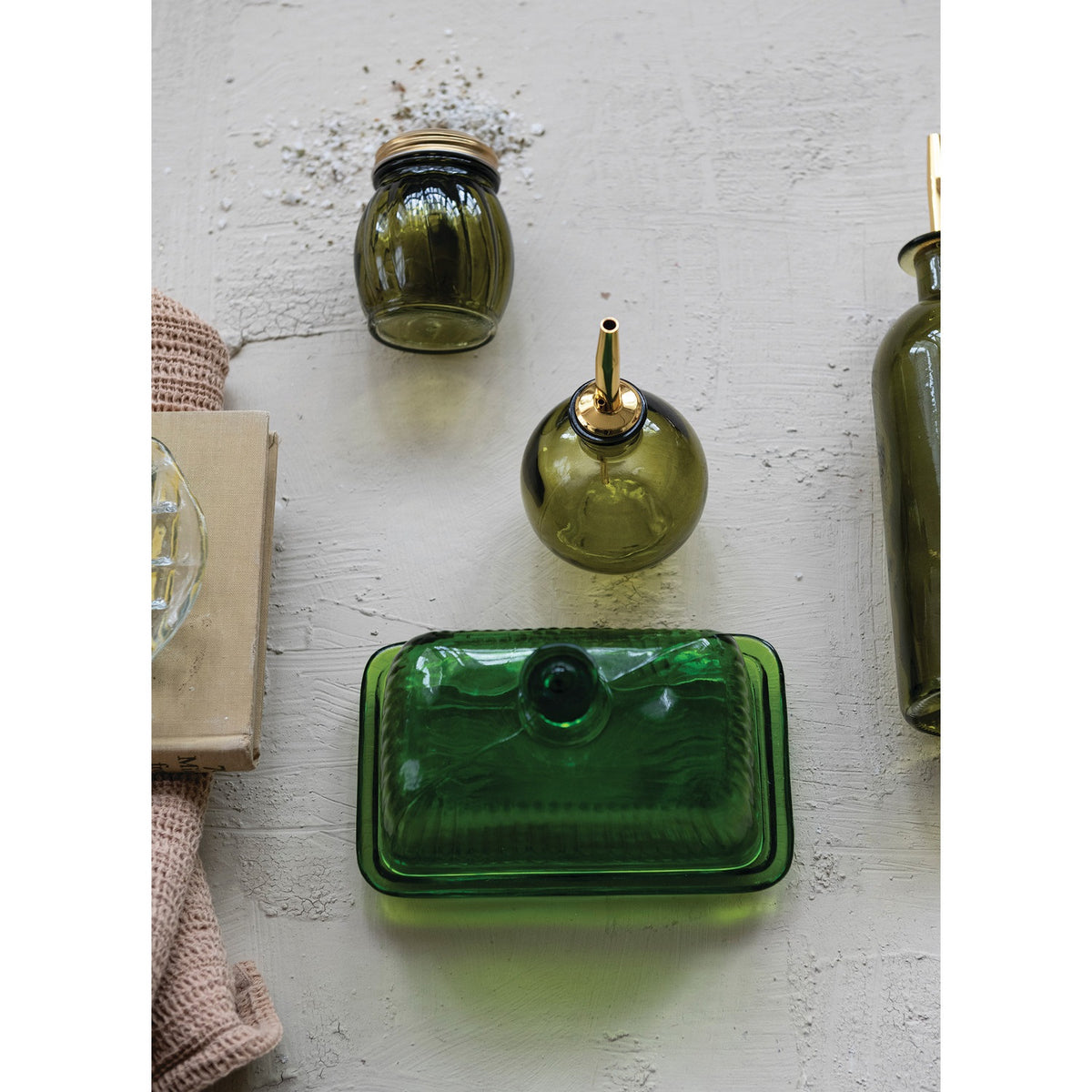 The GREEN PRESSED GLASS BUTTER DISH by CREATIVE COOP features a ribbed design, matching lid, and knob handle, displayed against a white background.