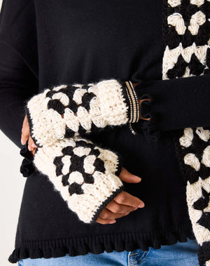The MERSEA - LA PAZ CROCHET FINGERLESS GLOVES by MERSEA, cream-colored with black borders and a central black geometric pattern, are displayed on a white background.