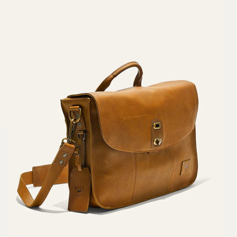 The WILL LEATHER GOODS Kent Messenger Bag in tan full-grain leather features a top handle, adjustable shoulder strap, front zip pocket, brass hardware, and laptop sleeve. Shown against a plain off-white background.