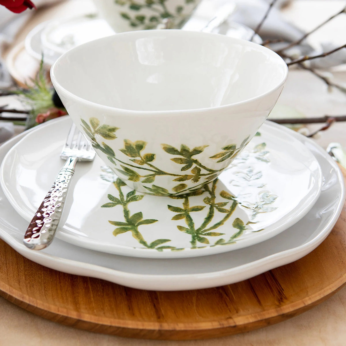 The VIETRI - Fauna Cereal Bowl is a small, white ceramic piece adorned with delicately painted green leaf designs on the exterior, evoking the lush greenery of Umbria. This bowl features a simple, elegant shape with a slightly flared rim and a smooth finish.