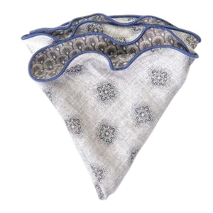 The EDWARD ARMAH Silk Reversible Pocket Circle in Gray Foulard/Feather features a light gray geometric pattern with blue accents and border, shown folded on a white background.