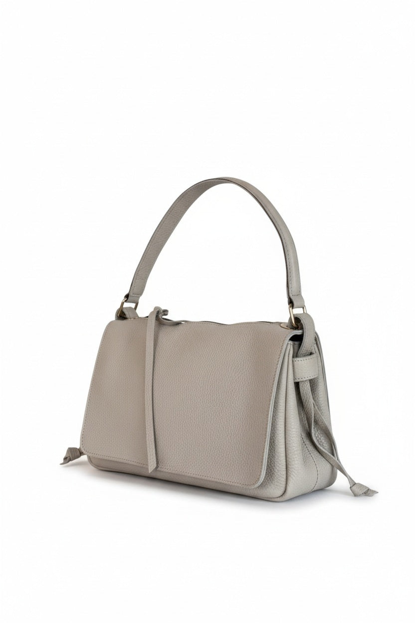 The OLIVEVE Remi Medium Slouchy Shoulder Bag in Lamp Buffalo Cowhide features a textured light beige leather, flap closure, short handle, and detachable crossbody strap, shown on a white background.