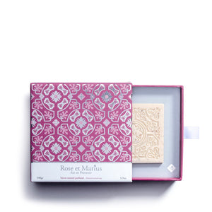 The ROSE ET MARIUS - A ROSE WINE UNDER THE ARBOR SCENTED SOAP GIFT BOX features a square, light pink soap bar with an ornate floral and geometric design, crafted from natural ingredients and displayed on a white background.