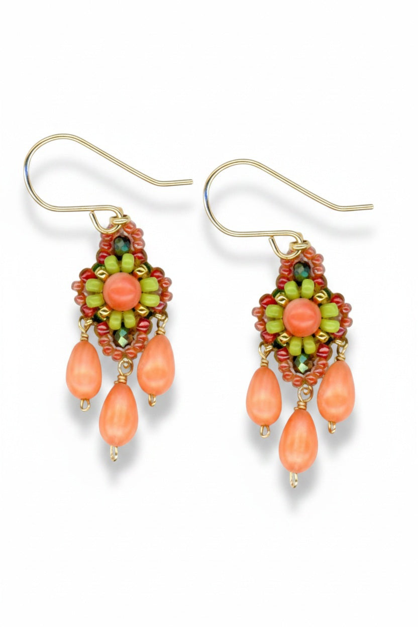 MIGUEL ASES - MIYUKI CRYSTAL BEAD EARRINGS from MIGUEL ASES, INC. feature a green, orange, and red beaded pattern with three teardrop-shaped orange beads dangling from the centerpiece and are finished with gold hooks for wearing.