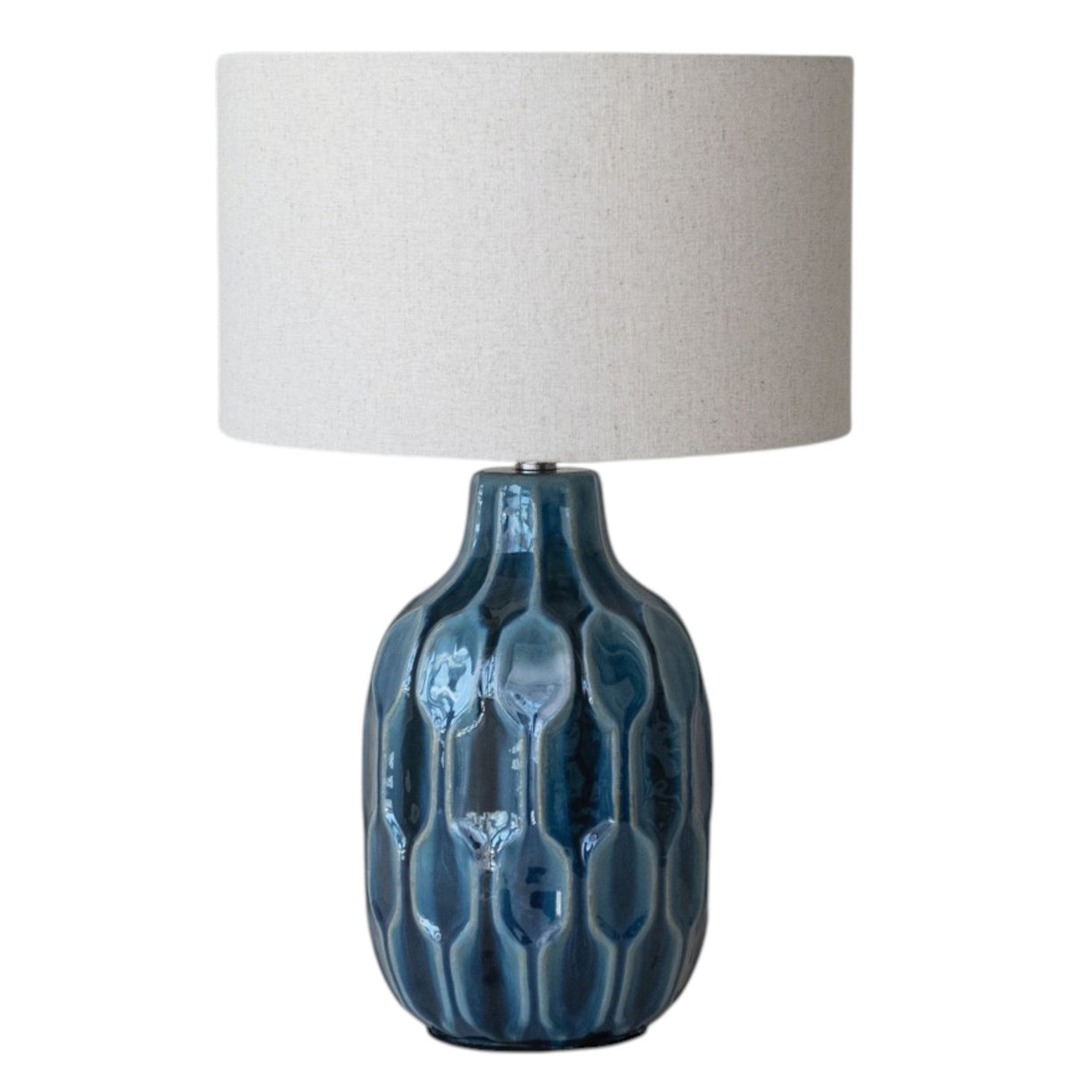 The CREATIVE COOP BLUE CERAMIC TABLE LAMP WITH LINEN SHADE features an embossed, reactive blue glaze base and a large round drum shade, shown against a plain white background.