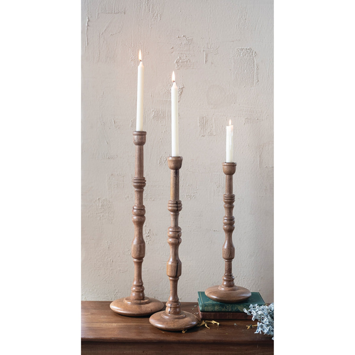 The TURNED MANGO WOOD TAPER HOLDER, MEDIUM by CREATIVE COOP features a tall, slender design with a round base, carved details, and a natural mango wood finish crafted in traditional turned woodwork.