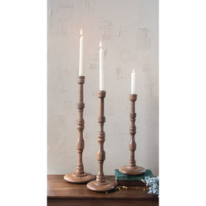 The TURNED MANGO WOOD TAPER HOLDER, MEDIUM by CREATIVE COOP features a tall, slender design with a round base, carved details, and a natural mango wood finish crafted in traditional turned woodwork.