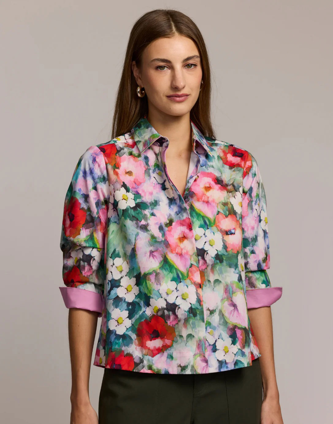 A woman with long brown hair wears the HINSON WU XENA 3/4 Sleeve Shirt in animal print, featuring black, tan, and cream hues. She pairs it with gold hoop earrings and stands against a plain background.