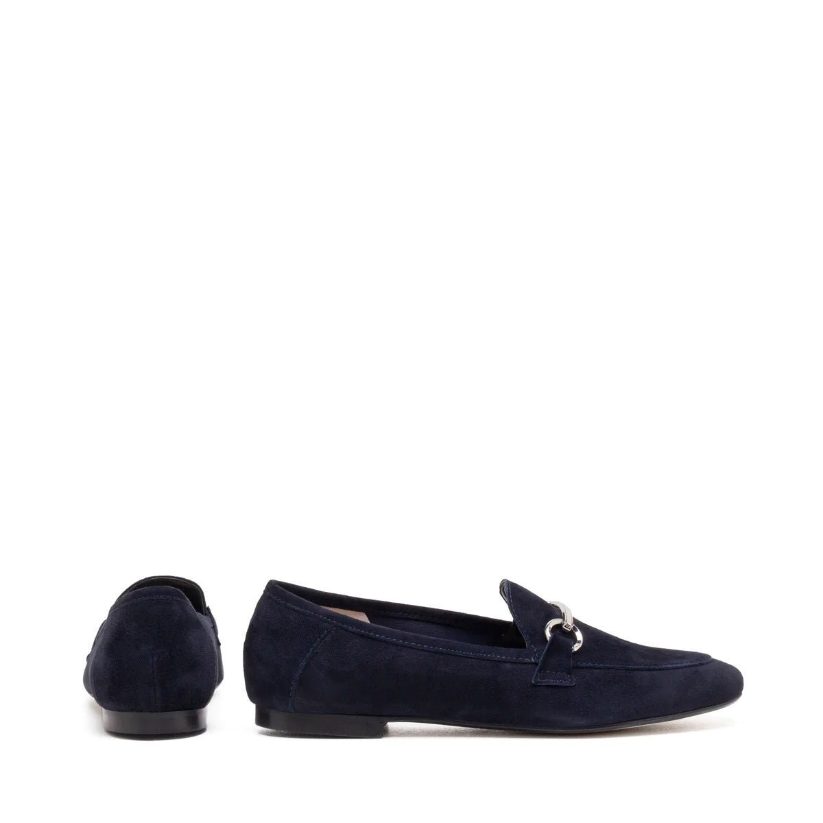 The MICHELE LOPRIORE - LEYLA LOAFER is a navy blue suede loafer adorned with a silver horsebit ornament on the vamp. Made in Italy and crafted from genuine leather, this shoe features a low heel and boasts a sleek, streamlined silhouette against a plain, off-white textured surface.