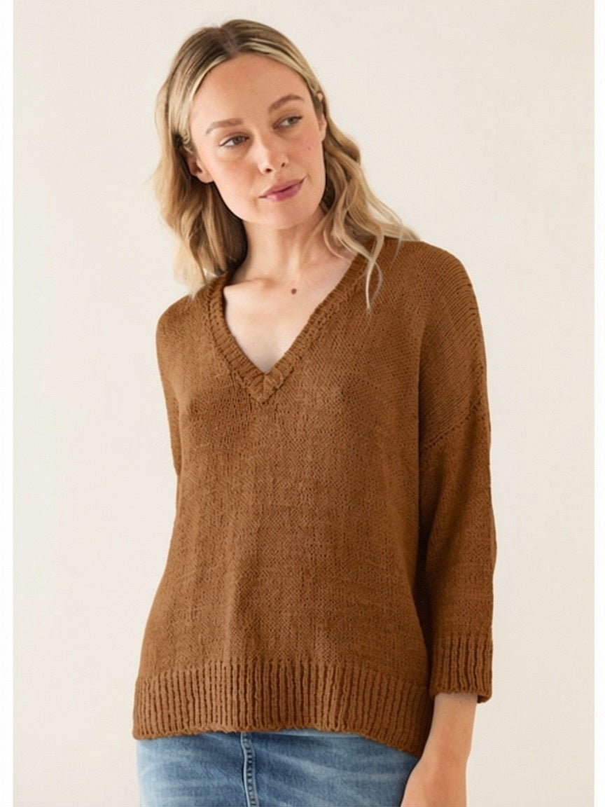 A woman with light hair models the BASE MILANO V NECK COTTON SWEATER in brown, styled in a relaxed fit with three-quarter sleeves and paired with blue jeans against a plain light background.