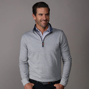 A man smiles against a plain gray backdrop, wearing the COLLARS AND CO Cloud Cotton Quarter Zip Pullover in Heather Grey over a white patterned shirt with dark pants.