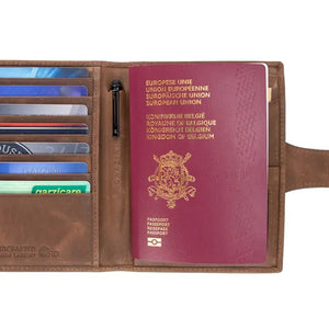 GARZINI RFID-blocking leather passport holder with AirTag compartment in brown, featuring a strap and snap button closure on a white background. The holder has a slightly worn, vintage look.