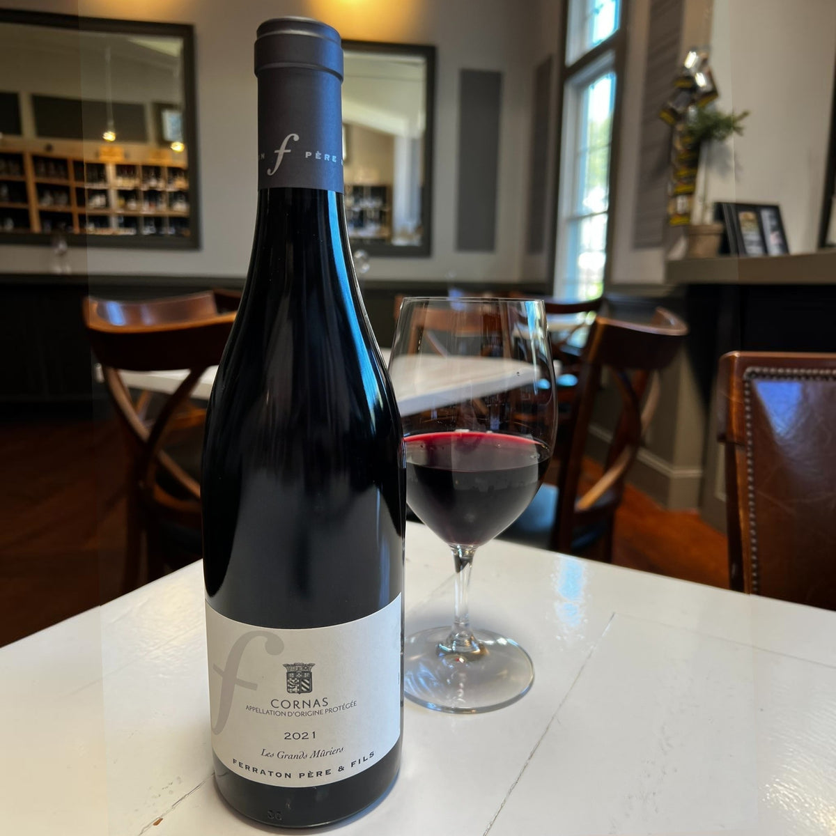 A bottle of FERRATON ‘LES GRANDS MURIERS’ CORNAS 2021 from WINE: 3 KEYS, an esteemed Northern Rhône Syrah, featuring a cream label and black capsule, stands upright against a white background.