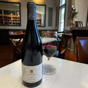A bottle of FERRATON ‘LES GRANDS MURIERS’ CORNAS 2021 from WINE: 3 KEYS, an esteemed Northern Rhône Syrah, featuring a cream label and black capsule, stands upright against a white background.