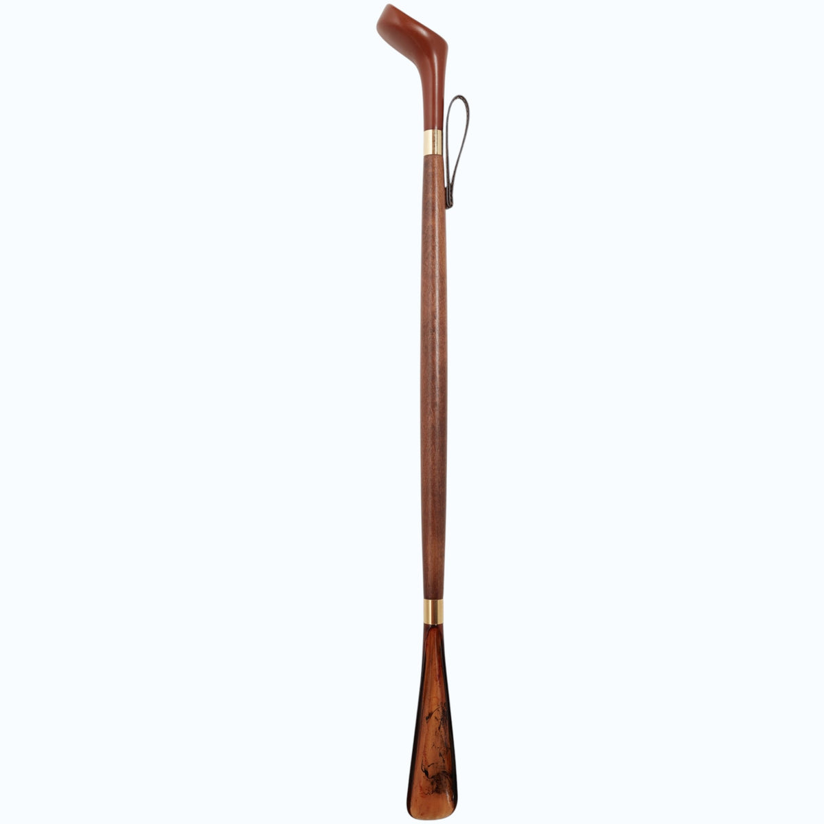 The HARVY CANES - GOLF DRIVER SHOE HORN by HARVY CANES is a long wooden shoehorn with a curved handle, brass accents, and a leather hanging loop, handcrafted in Spain and shown against a light gray background.