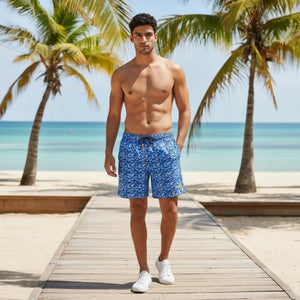 SAVE THE DUCK - ADEMIR SWIM TRUNKS IN BLUE SHARK: Quick-dry recycled polyester men's swim trunks featuring a blue and navy shark print, drawstring waistband, orange logo patch on the lower left leg, and plain light gray background.