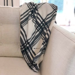 A folded, black-and-white plaid blanket from the FEARRINGTON SIGNATURE COLLECTION by STRAN PROMOTIONAL SOLUTIONS is displayed against a white background. The super-soft throw&#39;s sumptuous feel and classic pattern are prominently visible.