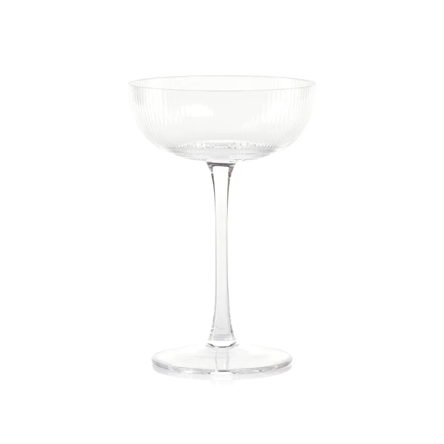 The OPTIC MARTINI GLASS from ZODAX is a clear, empty coupe glass with a capacity of 225 ml. It features a short stem and a wide, shallow bowl, adorned with subtle vertical ridges that add texture and elegance to its design. Set against a plain white background, its dimensions are perfectly showcased.