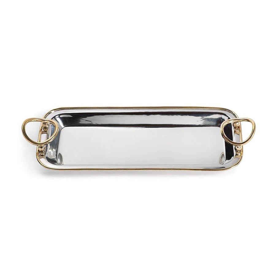 The POLISHED NICKEL AND GOLD TRAY by ZODAX is a rectangular decorative serving tray, crafted from polished nickel with gold trim accents and two circular gold handles, elegantly displayed on a light gray marble surface.