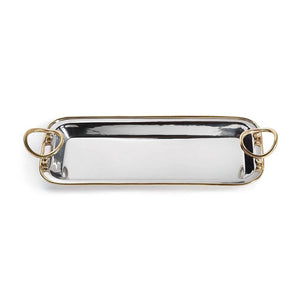 The POLISHED NICKEL AND GOLD TRAY by ZODAX is a rectangular decorative serving tray, crafted from polished nickel with gold trim accents and two circular gold handles, elegantly displayed on a light gray marble surface.