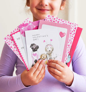 The E. FRANCES PAPER - DOGGIE DRESS-UP CLASSROOM VALENTINE SET features three dogs dressed festively: one in striped pajamas, another with a heart bandana, and a third with heart antennae. “Happy Valentine’s Day!” is displayed across the top against a backdrop of pink hearts, ideal for charming Valentines or envelopes.