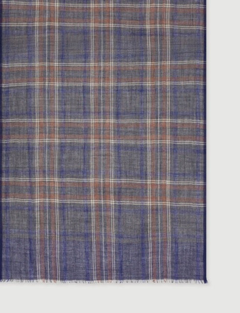 A man wearing a grey long-sleeve sweater and the HARTFORD - TARTAN WOOL SCARF IN INDIGO, GREY AND CAMEL stands against a white background, looking directly at the camera with his hands in his pockets—showcasing this classic men’s winter accessory from HARTFORD.