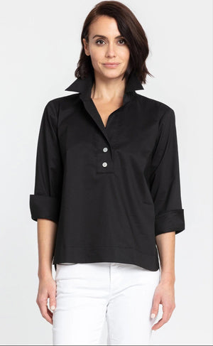 A person with short, dark hair is standing against a plain background, wearing the HINSON WU - AILEEN 3/4 SLEEVE TOP in black with a shirt collar and the sleeves rolled up, paired with white pants. The top features three buttons at the neckline. The individual is looking directly at the camera and smiling slightly.