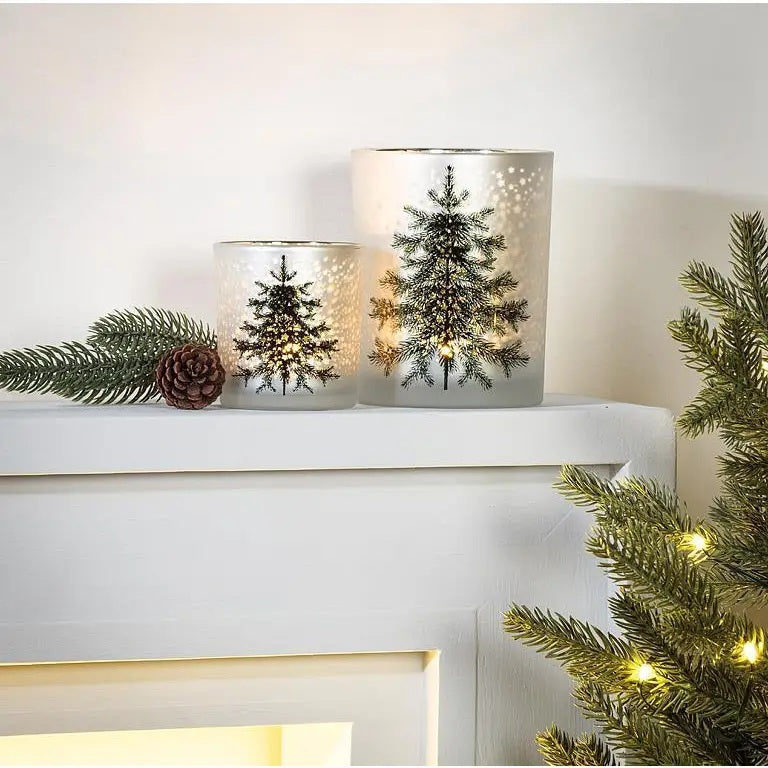 FROST TREE AND STARS VOTIVE HOLDER by ABBOTT, a frosted glass votive holder decorated with pine tree and star cutouts, illuminated from within to create a festive evergreen tree candle display.