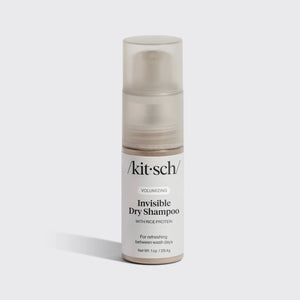 A bottle of KITSCH Volumizing Invisible Rice Protein Dry Shampoo stands upright on a light background. This non-aerosol, mess-free formula by KITSCH refreshes your hair with rice protein and comes with a clear cap and white label.