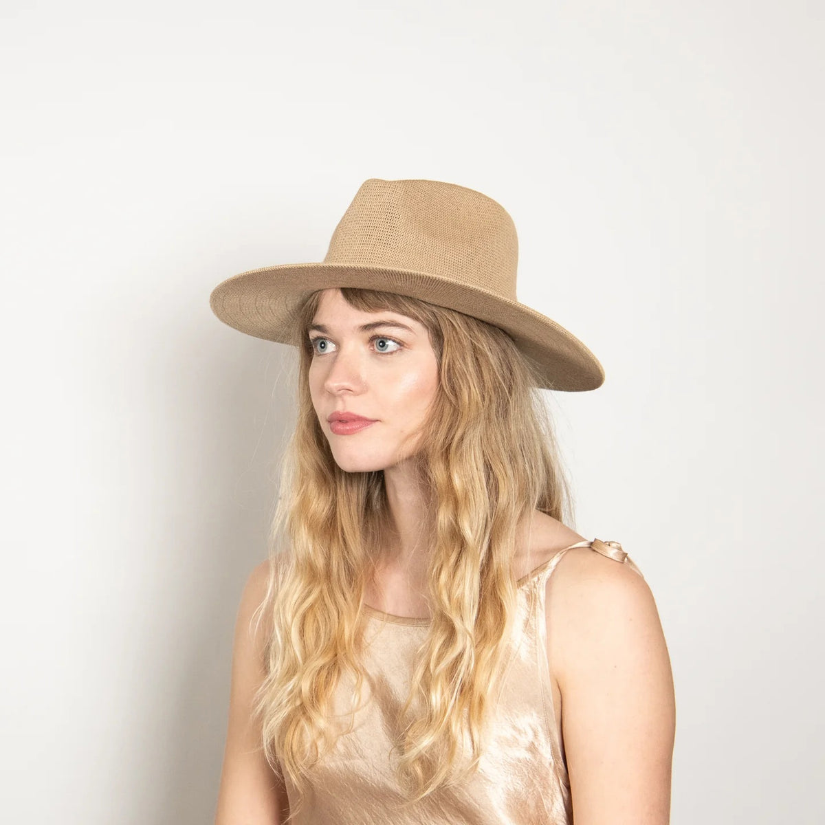 The WYETH HATS - Hudson Mesh Panama Hat in Tan by WYETH features a wide brim, woven straw design, genuine leather knotted trim around the crown, and an adjustable fit. Shown against a plain white background.