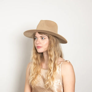 The WYETH HATS - Hudson Mesh Panama Hat in Tan by WYETH features a wide brim, woven straw design, genuine leather knotted trim around the crown, and an adjustable fit. Shown against a plain white background.